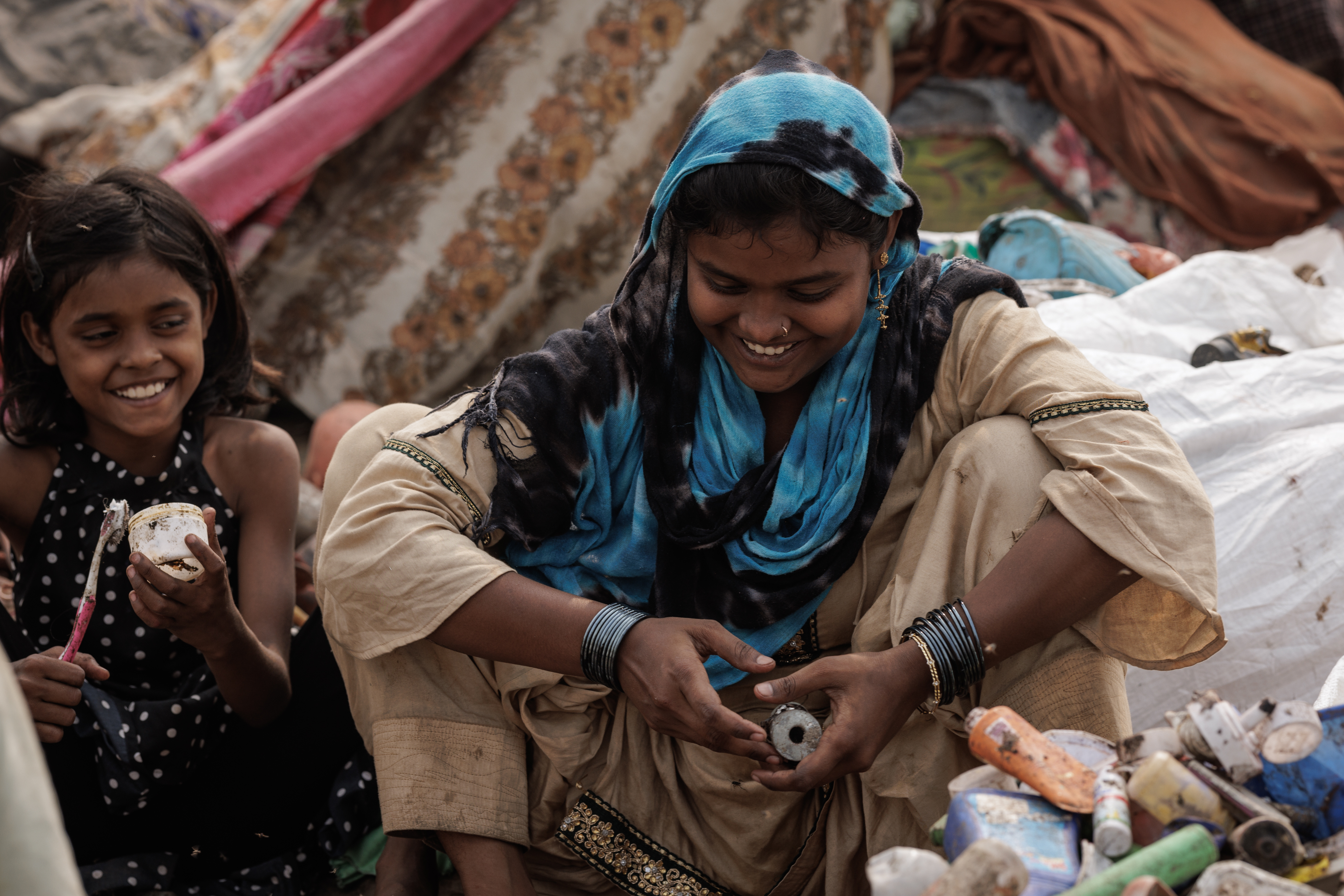 Woman and girl smiling among collected waste in the colony