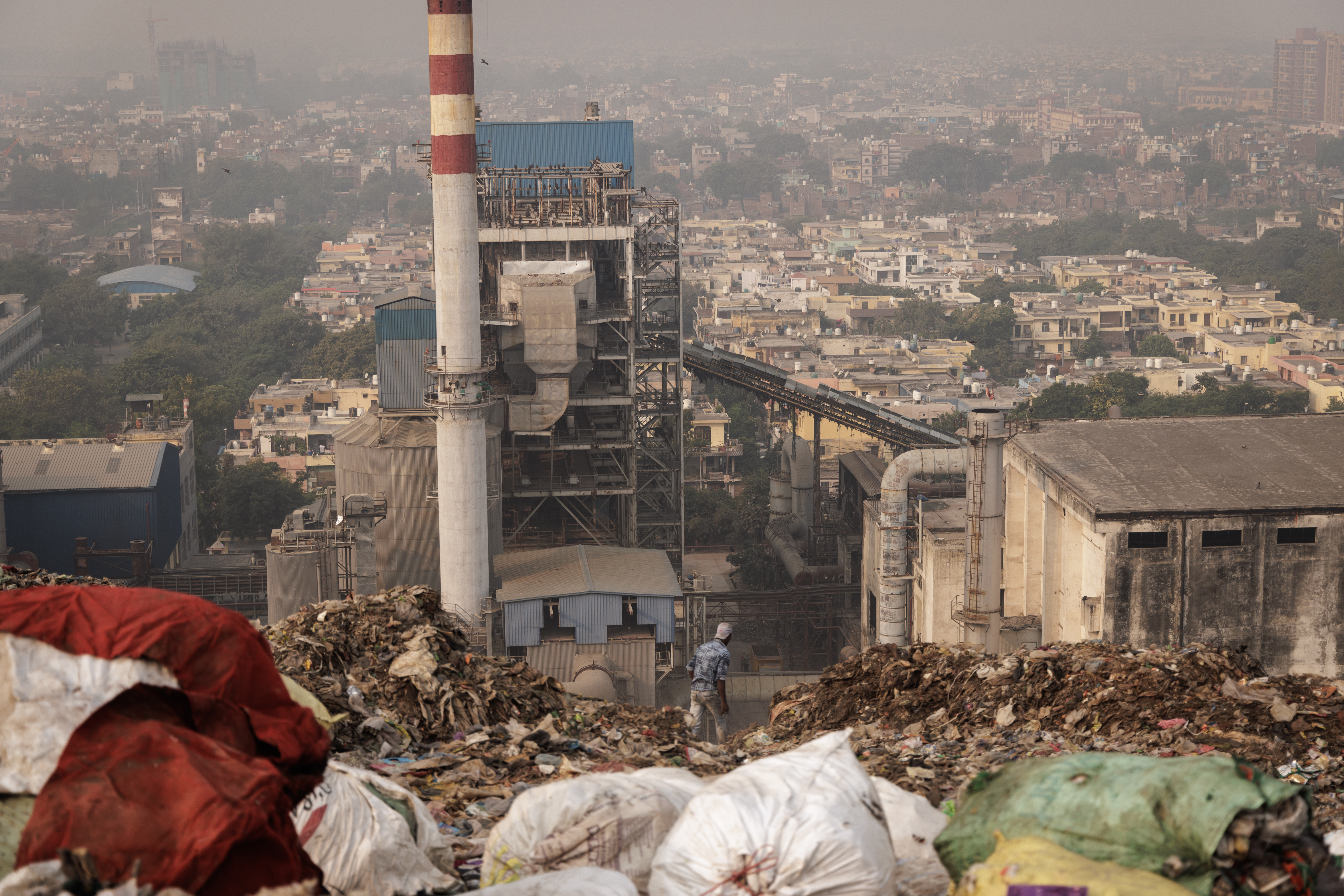 View from the summit of Ghazipur landfill — waste plant smokestack, Delhi skyline in haze