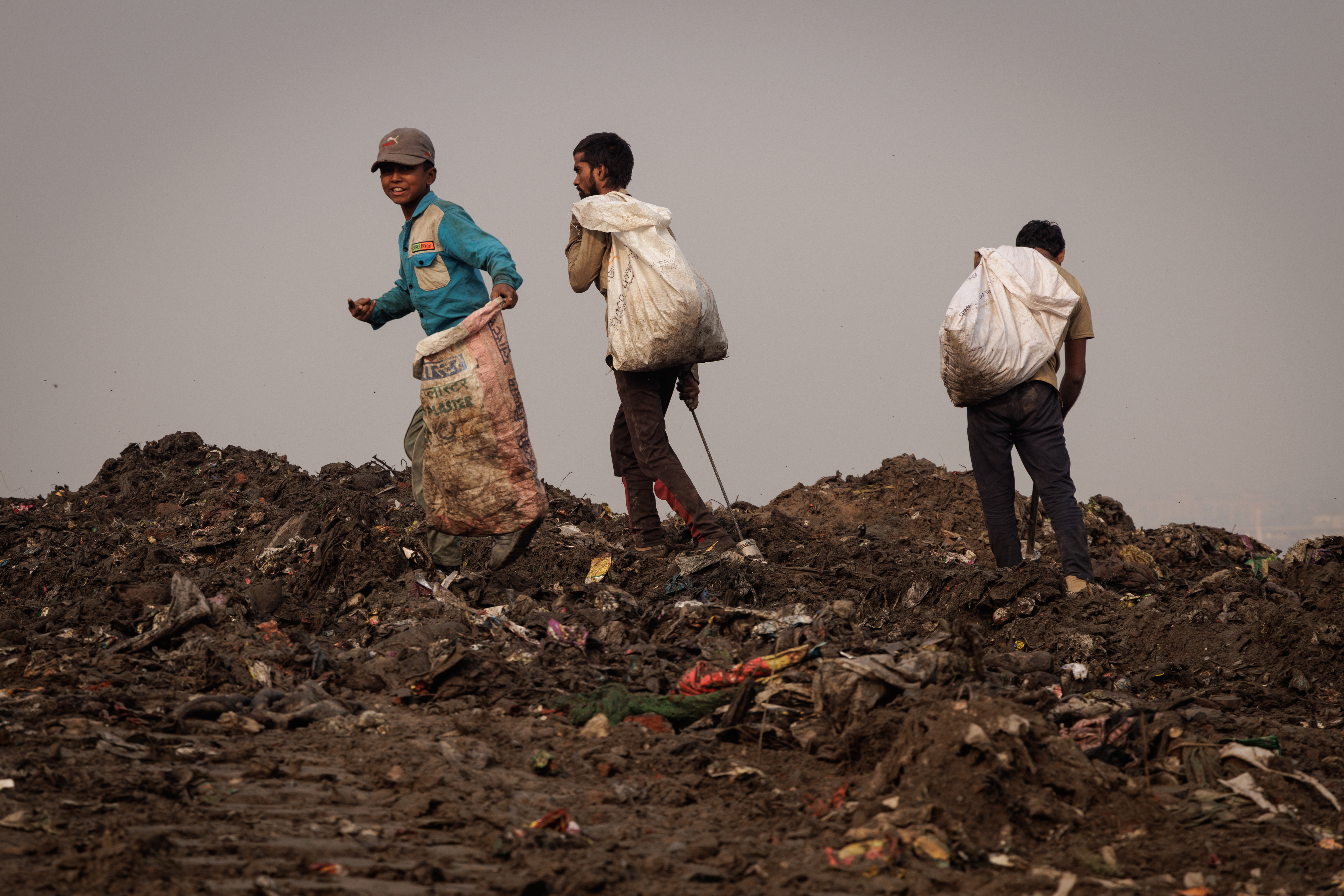 Three boys carrying full sacks across the ridge