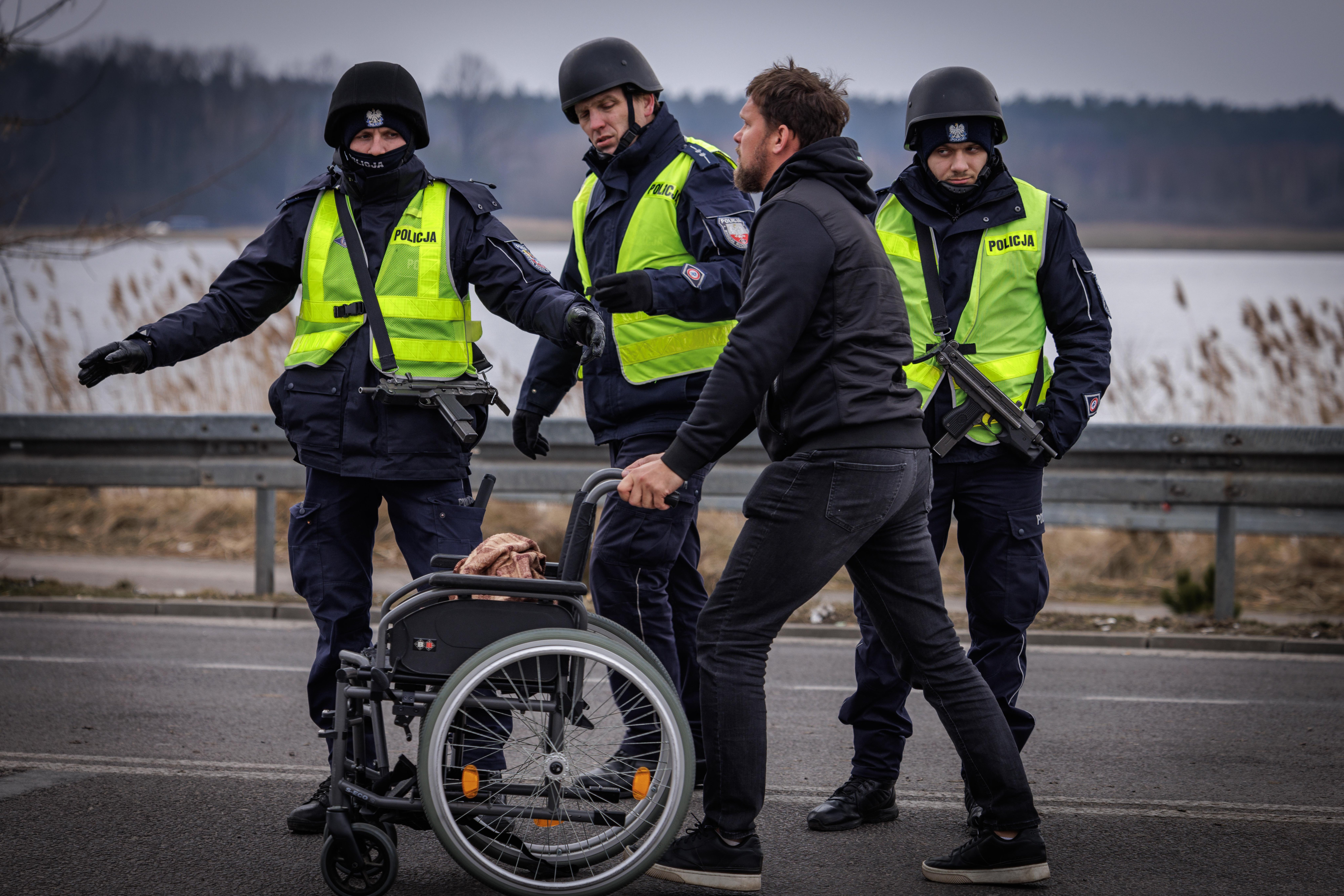Polish police helping push a wheelchair across the border road